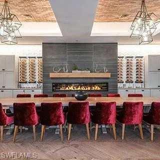 Dining space with a raised ceiling, a chandelier, a fireplace, brick ceiling, and light wood-type flooring
