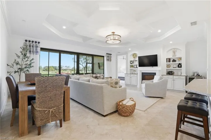 Living area with built in shelves, a fireplace, a chandelier, coffered ceiling, and recessed lighting