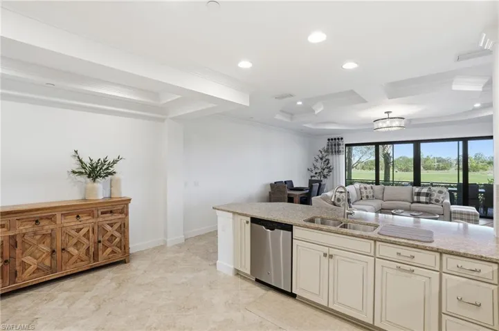 Kitchen with light stone counters, stainless steel dishwasher, open floor plan, crown molding, and recessed lighting