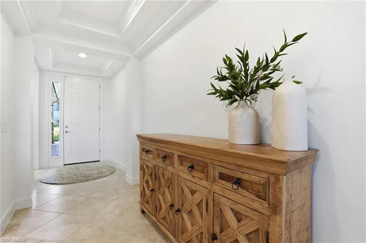 Entryway with crown molding, light tile patterned flooring, and recessed lighting