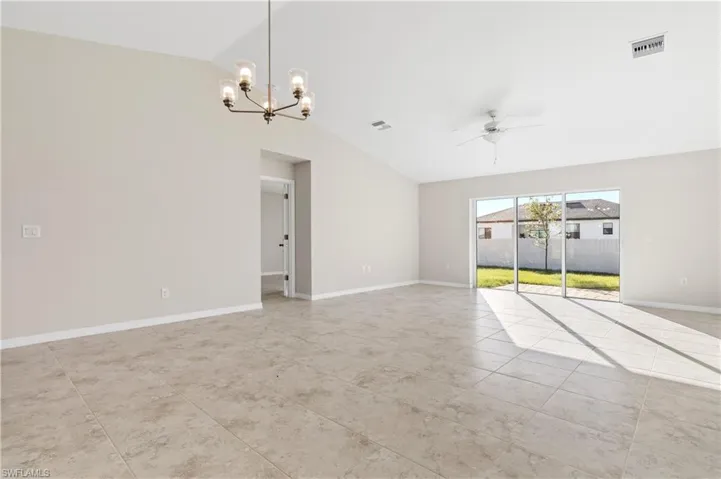 Unfurnished room with vaulted ceiling, a chandelier, ceiling fan, and light tile patterned flooring