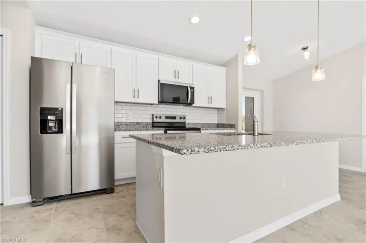 Kitchen featuring stainless steel appliances, light stone counters, white cabinets, decorative backsplash, and recessed lighting