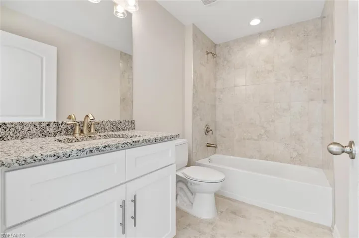 Bathroom with shower / washtub combination, vanity, light tile patterned floors, and recessed lighting