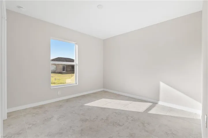 Empty room with baseboards and light tile patterned floors