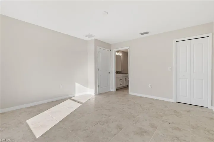 Unfurnished bedroom featuring connected bathroom, a closet, and light tile patterned floors