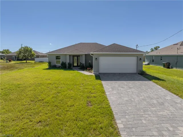 Single story home with a front yard, decorative driveway, and stucco siding