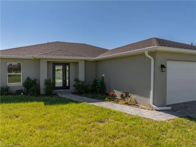 Ranch-style house with a front lawn, stucco siding, a garage, and roof with shingles