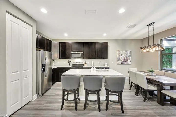 Kitchen featuring sink, hanging light fixtures, light hardwood / wood-style floors, a kitchen island with sink, and appliances with stainless steel finishes