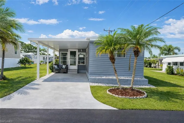 Manufactured / mobile home featuring a front lawn, an attached carport, driveway, and a patio