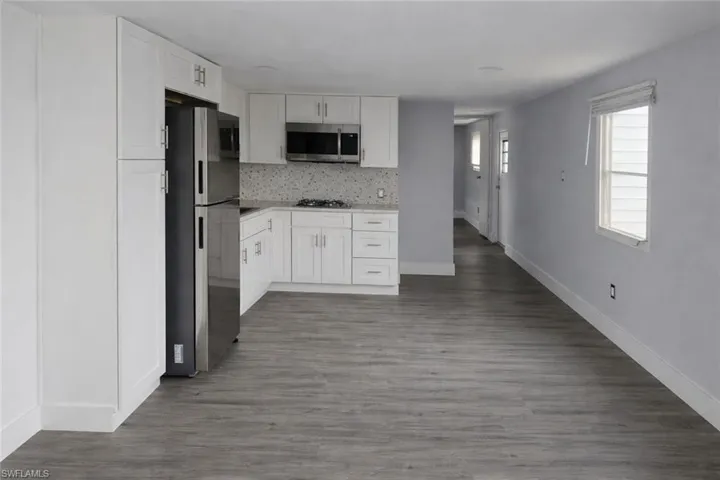 Kitchen featuring white cabinetry, stainless steel appliances, dark wood-style floors, and backsplash