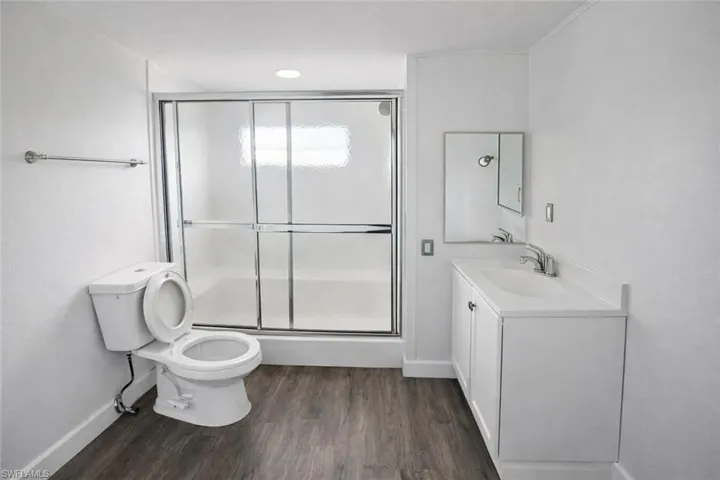 Full bath with a stall shower, vanity, and dark wood finished floors