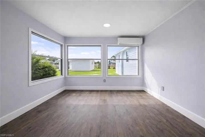 Empty room with dark wood-style floors and a wall mounted mini split