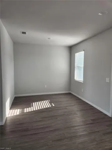 Empty room featuring dark wood-style floors and baseboards