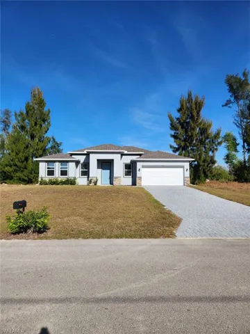Prairie-style home with stone siding, a front lawn, decorative driveway, and a garage