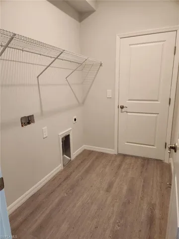 Laundry area with light wood-style flooring, hookup for a washing machine, and electric dryer hookup