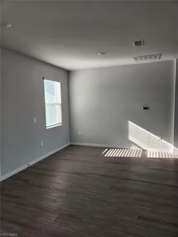 Spare room featuring baseboards and dark wood-style flooring