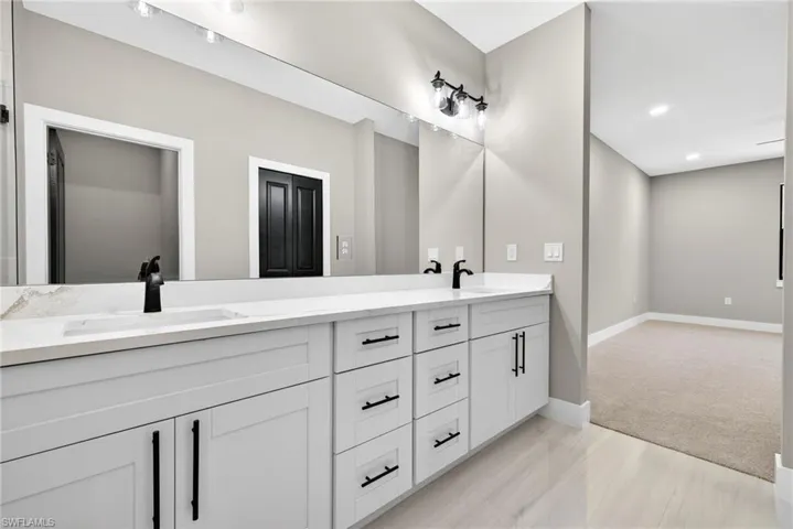 Bathroom with double vanity, light colored carpet, and recessed lighting