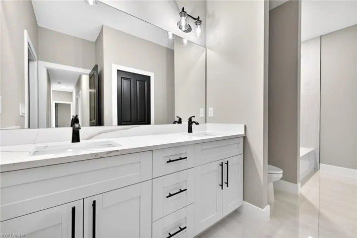 Bathroom with double vanity and baseboards