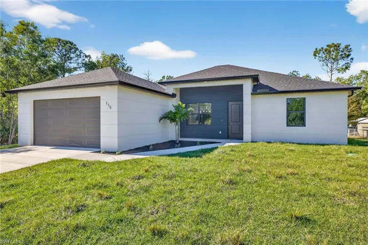 View of front of home featuring a front yard, an attached garage, and driveway