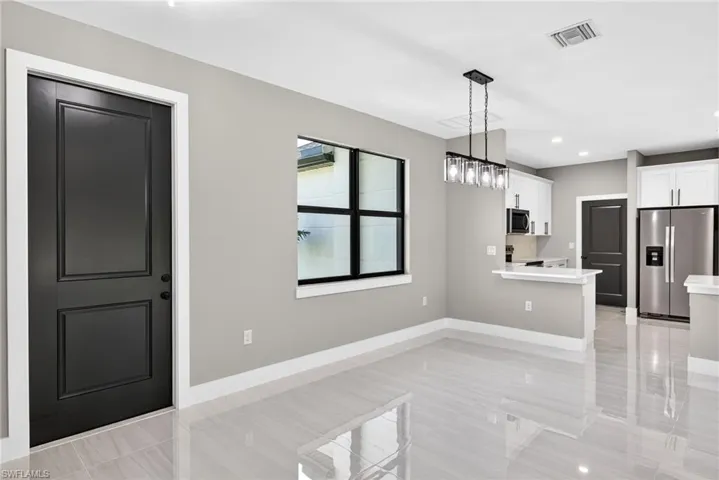 Kitchen featuring appliances with stainless steel finishes, white cabinets, hanging light fixtures, a peninsula, and recessed lighting