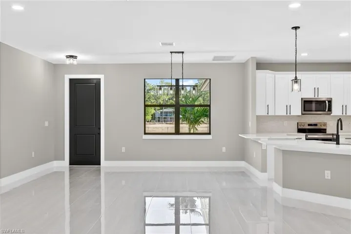 Kitchen featuring recessed lighting, hanging light fixtures, appliances with stainless steel finishes, white cabinetry, and light stone countertops