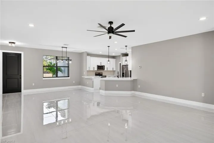Unfurnished living room featuring a ceiling fan, recessed lighting, and a chandelier