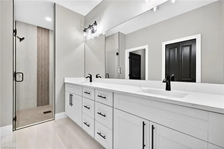 Bathroom with double vanity, a shower stall, and recessed lighting