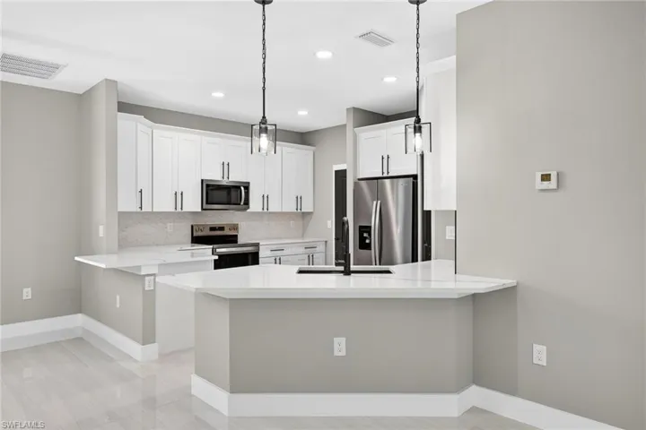 Kitchen featuring a peninsula, stainless steel appliances, white cabinets, pendant lighting, and light stone counters