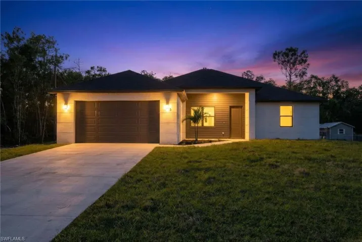 View of front of house with concrete driveway, an attached garage, and a yard
