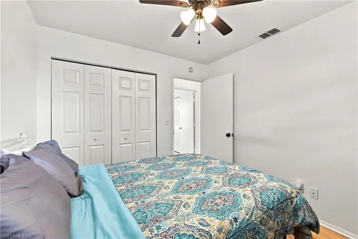 Bedroom featuring a ceiling fan with integrated lighting, wood-finish flooring, and white bi-fold closet doors