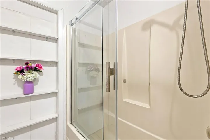 Glass-enclosed shower with a beige shower surround and integrated shower niches