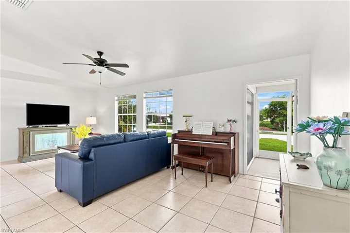 Open living space featuring tile flooring, white walls, and a ceiling fan with integrated lighting