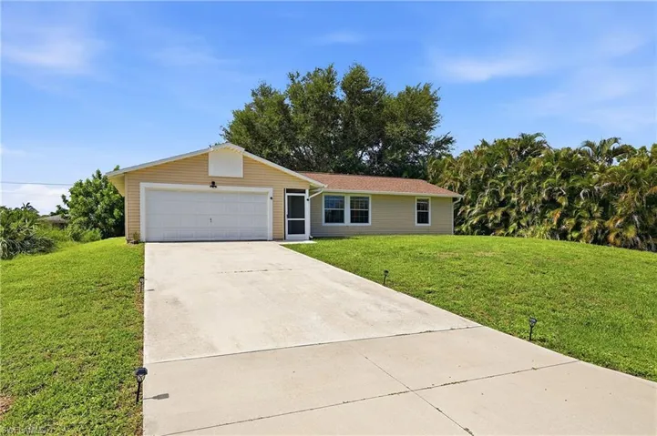 Single-story residence featuring light-colored siding, a two-car garage with a white door, and a concrete driveway