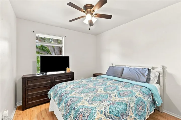 Bright room featuring wood-finish flooring, a ceiling fan with integrated lighting, and a white window with blinds