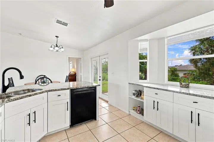 Kitchen featuring white cabinetry with granite countertops, a built-in dishwasher, and a bay window