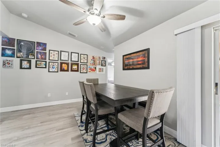 Dining area with lofted ceiling, a ceiling fan, light wood-type flooring, and baseboards
