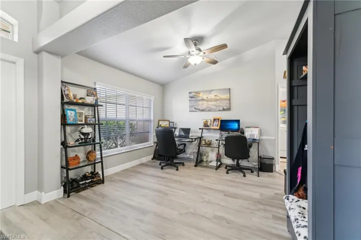Office area featuring lofted ceiling, light wood-style flooring, ceiling fan, and baseboards