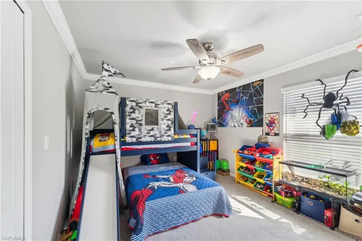 Bedroom featuring carpet floors, ornamental molding, and a ceiling fan