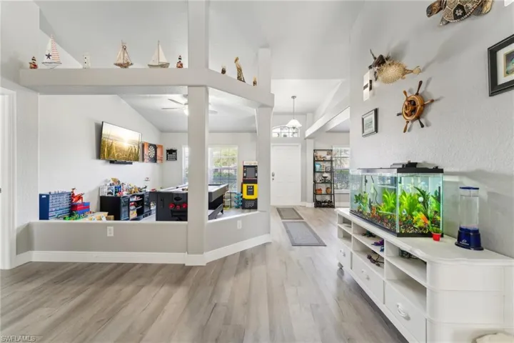 Living area with wood finished floors, lofted ceiling, a ceiling fan, and baseboards