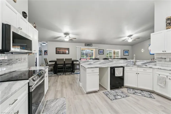 Kitchen with ceiling fan, stainless steel appliances, backsplash, and a peninsula