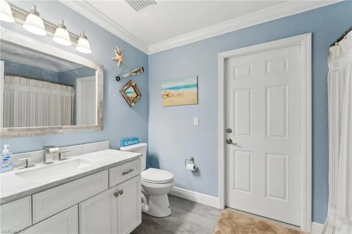 Full bathroom featuring vanity, toilet, crown molding, wood finished floors, and baseboards