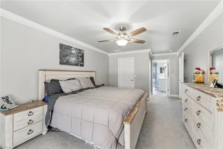 Bedroom with ornamental molding, light colored carpet, baseboards, and ceiling fan