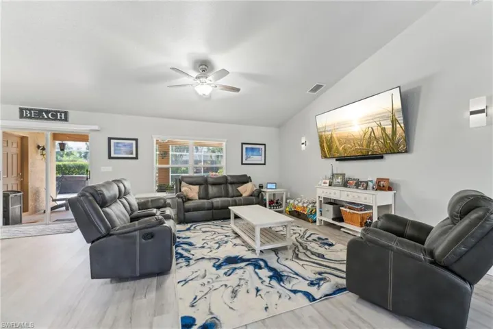 Living room with vaulted ceiling, wood finished floors, and a ceiling fan
