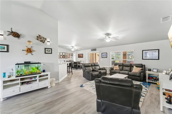 Living room with ceiling fan, vaulted ceiling, light wood-style flooring, and baseboards