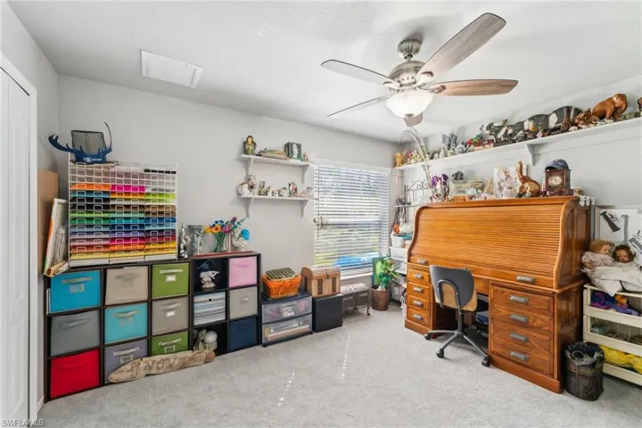 Carpeted home office featuring ceiling fan