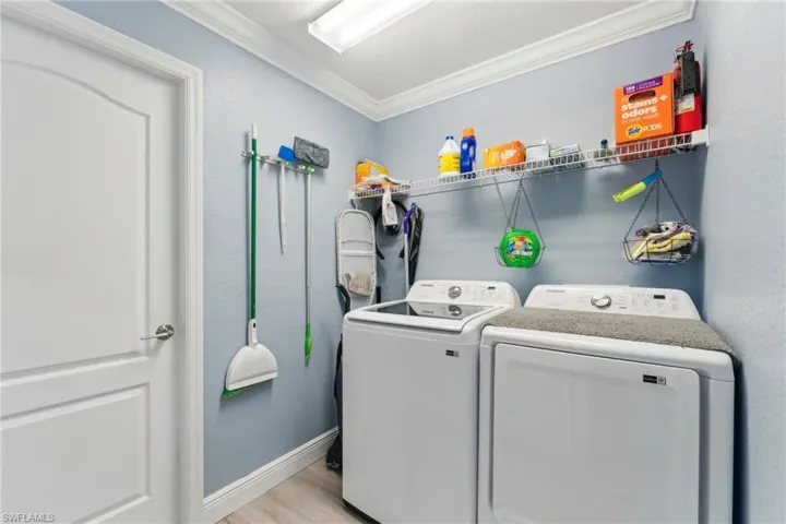 Washroom featuring independent washer and dryer, ornamental molding, light wood finished floors, and baseboards