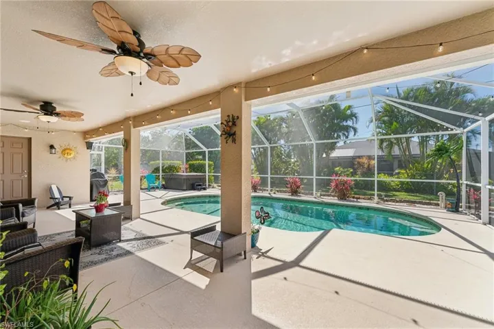 Swimming pool with a hot tub, a patio, a lanai, an outdoor living space, and ceiling fan