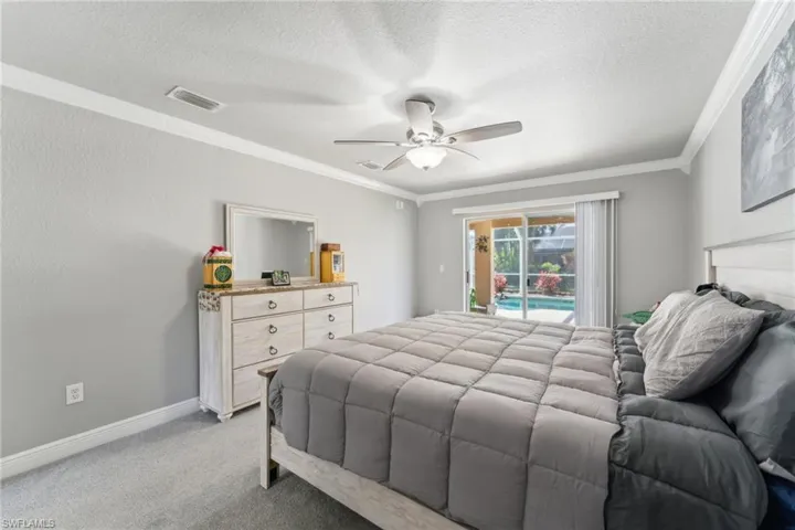 Bedroom with access to outside, a textured ceiling, ornamental molding, light colored carpet, and ceiling fan