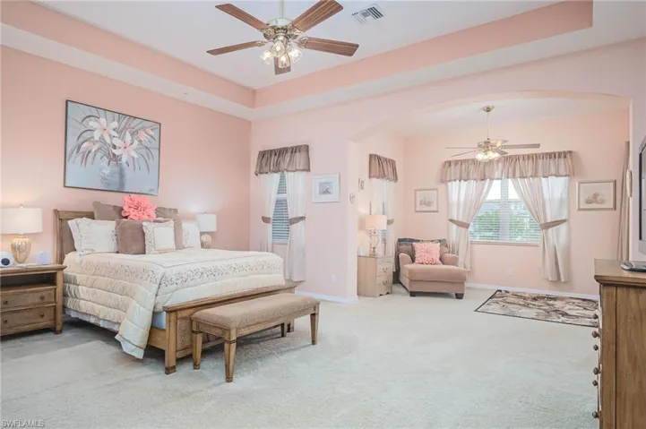 Bedroom featuring a tray ceiling, light carpet, and ceiling fan