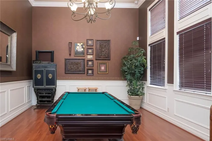 Recreation room featuring an inviting chandelier, billiards, ornamental molding, plenty of natural light, and wood-type flooring